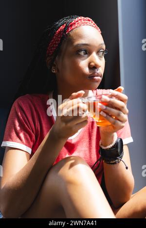 Eine junge Afroamerikanerin genießt eine Tasse Tee und schaut nachdenklich Stockfoto