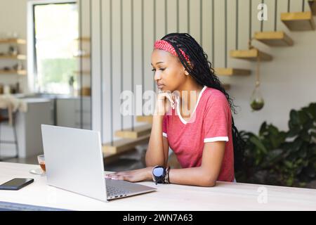Eine junge afroamerikanische Frau konzentriert sich intensiv auf ihren Laptop-Bildschirm Stockfoto