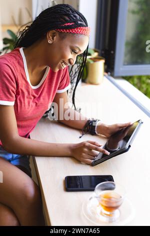 Eine junge Afroamerikanerin lächelt, während sie ein Tablet benutzt Stockfoto