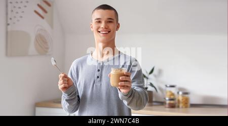 Glücklicher junger Mann mit leckerer Nussbutter in der Küche Stockfoto