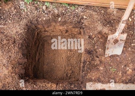 Loch in einem Boden, vorbereitet für das Pflanzen oder Bauen, Grube in einem Boden mit Schaufel Stockfoto