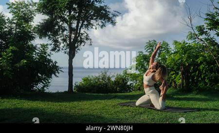 Banner einer jungen Latina macht Yoga auf einer Klippe nahe der Küste. Stockfoto