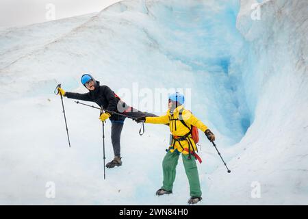 Ein Paar hält Wanderstöcke und macht Yoga-Posen vor einer Eisgrube. Nehmen Sie Die Abfahrt Glacier. Kenai Fjords National Park. Alaska. Stockfoto