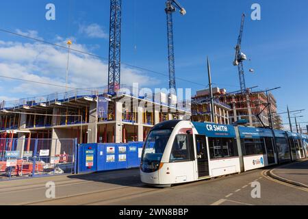 Eine Straßenbahn in Edinburgh auf dem Ocean Drive in Leith mit einer Baustelle dahinter. Stockfoto