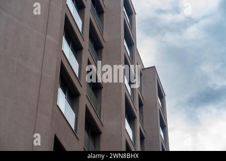 Braune Wandfassade. Gebäude Balkone mit Sicherheitszaun aus Glas inmitten des dramatischen blauen Himmels. Stockfoto