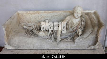 Römischer Sarkophag mit Statue eines liegenden Jungen, der eine Frucht hält. Rom. Nationales Römisches Museum (Diokletianbäder). Rom. Italien. Stockfoto