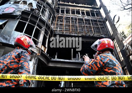 Dhaka, Wari, Bangladesch. März 2024. Einen Tag nach einem Brandunfall versammeln sich Menschen in der Nähe eines Geschäftsgebäudes, während Feuerwehrleute und forensische Experten am 1. März 2024 den Standort in Dhaka inspizieren. Die Feuerwehr in Bangladesch sagte am 1. März, dass die eklatanten Sicherheitsverstöße für eine Flamme im Restaurant Dhaka verantwortlich seien, bei der 45 Menschen getötet wurden, wobei unter denen, die in kritischem Zustand ins Krankenhaus kamen, wahrscheinlich mehr Todesfälle zu beklagen seien. (Kreditbild: © Habibur Rahman/ZUMA Press Wire) NUR REDAKTIONELLE VERWENDUNG! Nicht für kommerzielle ZWECKE! Stockfoto