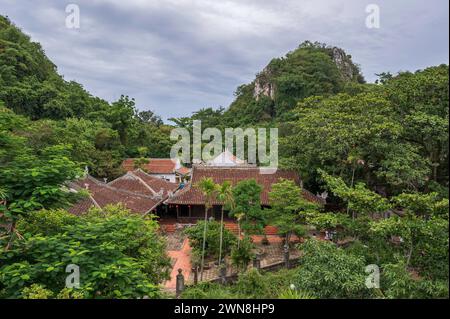 Blick auf einen Buddisten Tempel, eingebettet in tropisches Laub und Berggipfel. Die Lage ist die berühmte Marble Mouintains, Vietnam Stockfoto