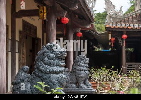 Schließen Sie die Skulptur des Lion Guardian am buddhistischen Tempel auf dem Marbel Mountian, Zentrum Vietnams. An der Stuktur hängen rote Laternen Stockfoto