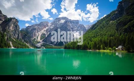 Pragser Wildsee in den Dolomiten, Italien. Weitwinkelblick über den türkisfarbenen See, der von Nadelbäumen umgeben ist. Mächtige Berge im Hintergrund. Es gibt ein weit entferntes Boot auf dem See und eine kleine Kapelle am Ufer. Stockfoto