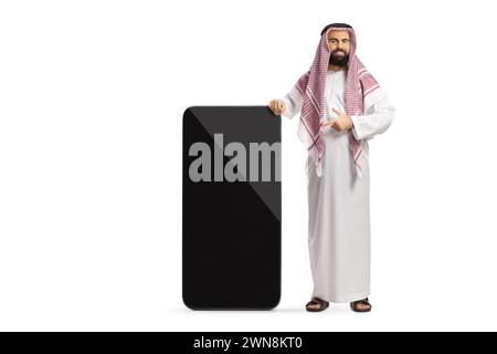 Saudischer arabischer Mann in ethnischer Kleidung, der auf ein großes Handy mit leerem Bildschirm auf weißem Hintergrund zeigt Stockfoto