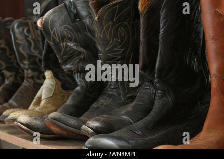 Die Stiefel sind ordentlich in einer Reihe auf einer Holzbank angeordnet Stockfoto