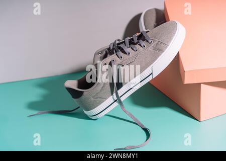 Graue Sneakers aus Stoff mit weißen Gummisohlen vor der Box Stockfoto