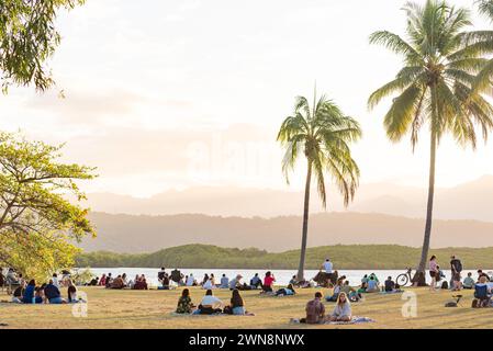 Am späten Nachmittag versammelten sich die Menschen in dem von Palmen gesäumten Park am Eingang zu Dixon Inlet und Port Douglas im Norden von Queensland, Australien Stockfoto