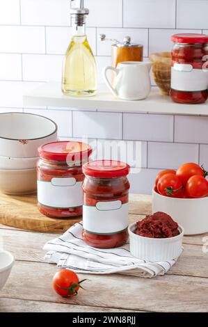 Tomatenpaste in einem Glas und einer Schüssel auf dem Küchentisch Stockfoto