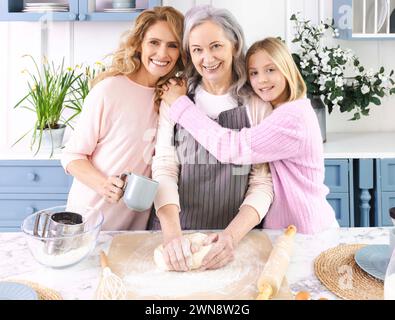 Porträt einer glücklichen Familie. Mutter und Enkelin besuchen Großmutter in ihrer Küche, sie kochen köstliche Teiggerichte zusammen, umarmen und haben Stockfoto