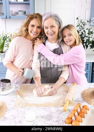 Porträt glücklicher Frauen aus drei Generationen von Familien, die Zeit zusammen in der Küche verbringen, während sie Teiggerichte wie Brot, Croissants, Kuchen zubereiten Stockfoto