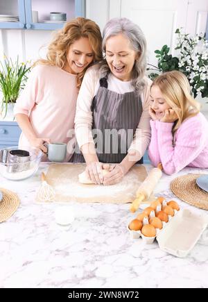 In der schönen Küche genießen Oma, Mutter und Enkelin gute Zeit zusammen, während sie Teig machen Stockfoto
