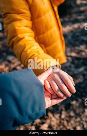 Die linke Hand der Frau hält die Hand eines Kindes an einem sonnigen Tag, Nahaufnahme Stockfoto