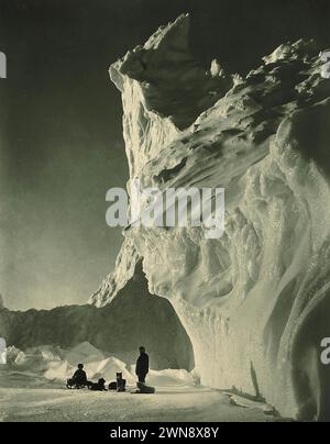 Vintage-Antarktis-Fotografie von Herbert George Ponting um 1911. Entdecker mit Schneehunden, die an einem riesigen Gletscher stehen. Stockfoto