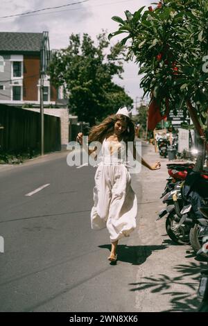 Eine junge Frau mit langen Haaren läuft die Straße auf Bali entlang. Stockfoto