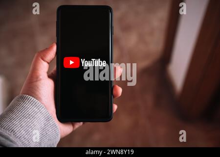 SPANIEN - 23. Februar 2024: Frau mit Smartphone und YouTube-Logo auf dem Bildschirm. Stockfoto