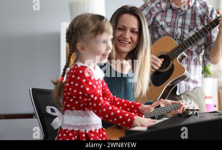 Eltern spielen Gitarre, Tochter auf Synthesizer Stockfoto
