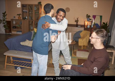 Gruppe von Freunden, die sich während der Hausfeier mit Blitz umarmen und begrüßen Stockfoto