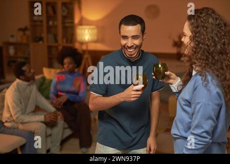 Porträt eines jungen Mannes, der fröhlich lacht und während der Hausfeier Drinks und Gespräche genießt, für Erwachsene Kopierraum Stockfoto