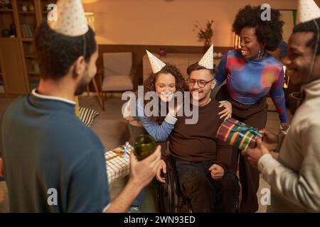 Hochwinkel-Porträt eines Mannes mit Behinderung, der Geburtstag mit verschiedenen Gruppen von Freunden während der Hausfeier feiert Kopierraum Stockfoto