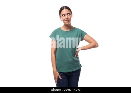 Junge traumhafte, schöne Brünette Dame mit Ponytail-Frisur in grünem T-Shirt und Jeans nachdenklich gekleidet Stockfoto