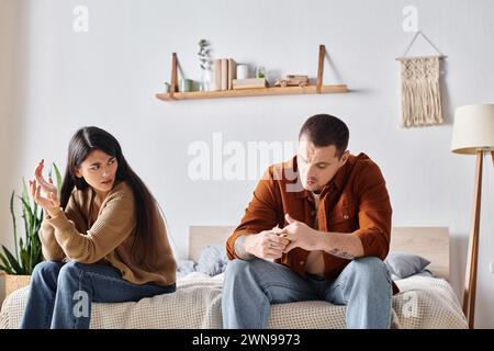 Frustriertes multiethnisches Paar, das zu Hause im Schlafzimmer sitzt und streitet, Scheidungskonzept Stockfoto