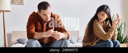 Verärgerte asiatische Frau sitzt und streitet mit ihrem Mann im Schlafzimmer zu Hause, horizontales Banner Stockfoto