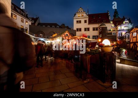 Nachtszene eines lebhaften Weihnachtsmarktes mit festlich beleuchteten Gebäuden und verschwommenen Passanten, dem Dresdner Weihnachtsmarkt Stockfoto