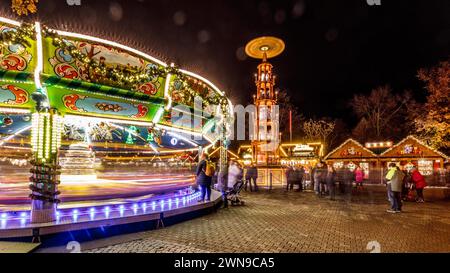 Farbenfrohes Karussell bei Nacht auf einem Weihnachtsmarkt, festlich beleuchtet mit einem Turm im Hintergrund, Erfurter Weihnachtsmarkt Erfurt Stockfoto