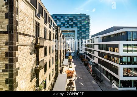 Blick auf eine städtische Straße, flankiert von Gebäuden mit einem Wolkenkratzer im Hintergrund, Kranhaeuser Köln Stockfoto