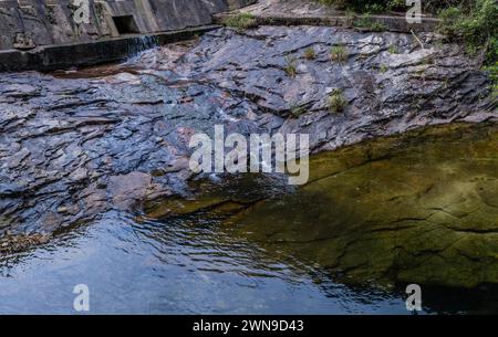 Wasser aus dem Überlauf, das über große flache Granitschichten in das Flussbecken in Südkorea fließt Stockfoto