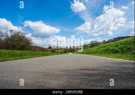 Eine leere Landstraße führt durch eine ruhige, grüne Landschaft unter bewölktem Himmel, Deilbachtal, Velbert, Mettmann, Nordrhein-Westfalen Stockfoto