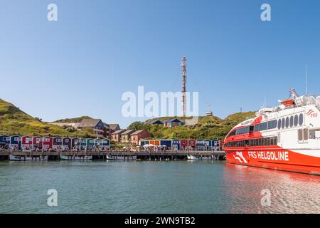 Promenade mit hölzernen Hummerhütten und Fähre im Hafen von Helgoland, Insel in der Deutschen Bucht, Nordsee, Deutschland Stockfoto