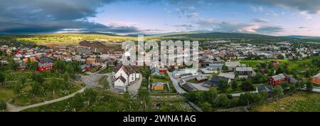 Das weitläufige Panorama der Drohne fängt Roros, Norwegen, im Sommer mit historischen Gebäuden ein, eingebettet in lebendiges Grün unter einem dynamischen Himmel Stockfoto