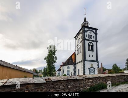 Die Kirche Roros steht hoch vor einem bewölkten Himmel, ihr Uhrenturm ist ein markantes Merkmal inmitten der historischen Gebäude dieser norwegischen Stadt Stockfoto