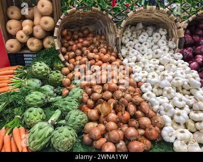 Knoblauch, weiße Zwiebeln, rote Zwiebeln und Artischocken, die in Korbkörben in Supermärkten verkauft werden Stockfoto