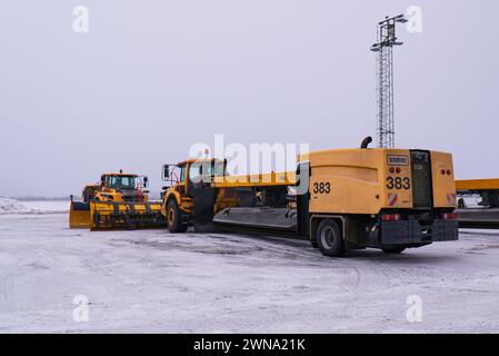 Eine Pflug-, Kehrer- und Blasmaschine (Schneepflug) am Flughafen Umeå, Swedavia Flughäfen, gelb, von Schmidt aus, wartet auf einen bevorstehenden Schneefall. Stockfoto