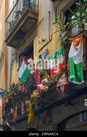 Ein städtischer Balkon mit mexikanischen Flaggen und traditioneller Dekoration in einer engen Gasse in der Stadt Barcelona in Katalonien Stockfoto