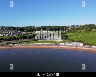 Drohnenfoto von Goodrington Sands Beach in der Nähe von Paignton Devon. Ein ruhiger, blauer Sandstrand mit einer langen Reihe von Strandhütten und einem klaren blauen Himmel Stockfoto