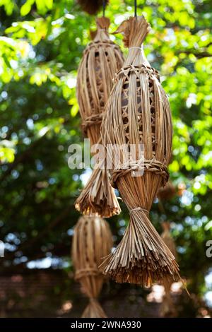 Eine Gruppe traditioneller vietnamesischer Flechtlaternen hängen draußen in einem Park. Mehrere Lampenschirme aus Rattan mit rustikalem und umweltfreundlichem Design Stockfoto