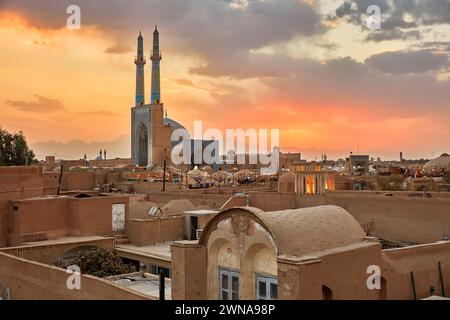 Blick von der Dachterrasse auf die Jameh-Moschee und alte lehmziegelgebäude im historischen Viertel Fahadan bei Sonnenuntergang. Yazd, Iran. Stockfoto