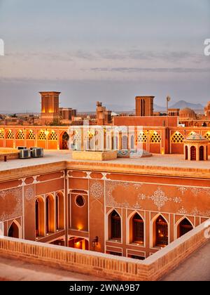 Blick von der Dachterrasse auf die alten lehmhäuser, die bei Dämmerung im historischen Viertel Fahadan in Yazd, Iran, beleuchtet werden. Stockfoto