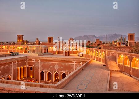 Blick von der Dachterrasse auf alte lehmziegelgebäude, beleuchtet bei Dämmerung im historischen Viertel Fahadan in Yazd, Iran. Stockfoto