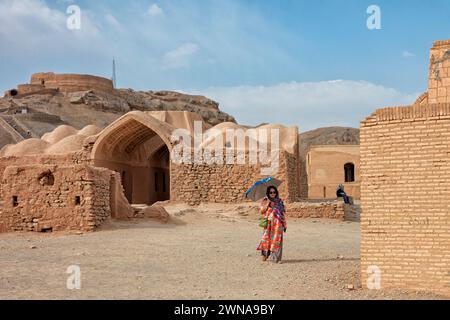 Frau mit Sonnenschirm spaziert in den Zoroastrian Towers of Silence (Dakhmeh) in Yazd, Iran. Die Zoroastrier glauben, dass Erde, Feuer und Wasser heilig sind Stockfoto